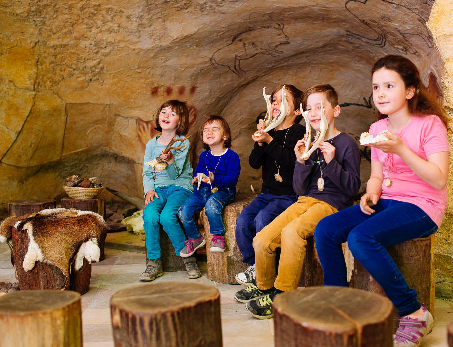 Kinder sitzen in einer Höhle im Neanderthal Freilichtmuseum