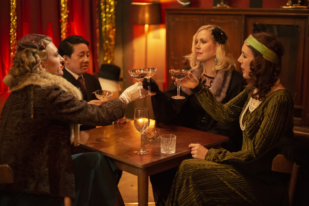 vier schauspieler:innen gekleidet in 20er jahre abendgarderobe die im exploria alkohol trinken