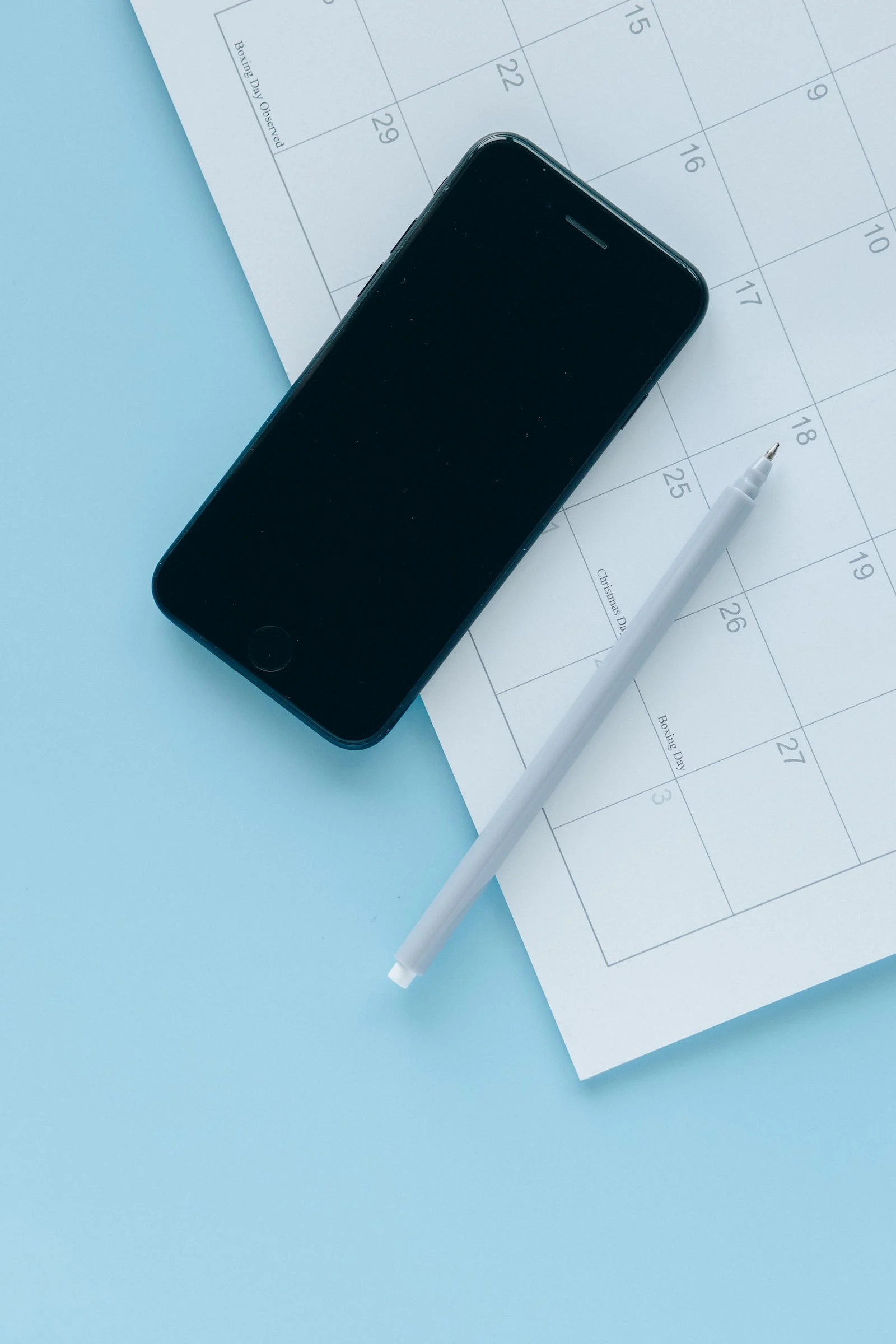 ein smartphone ein stift und ein kalender auf einem tisch