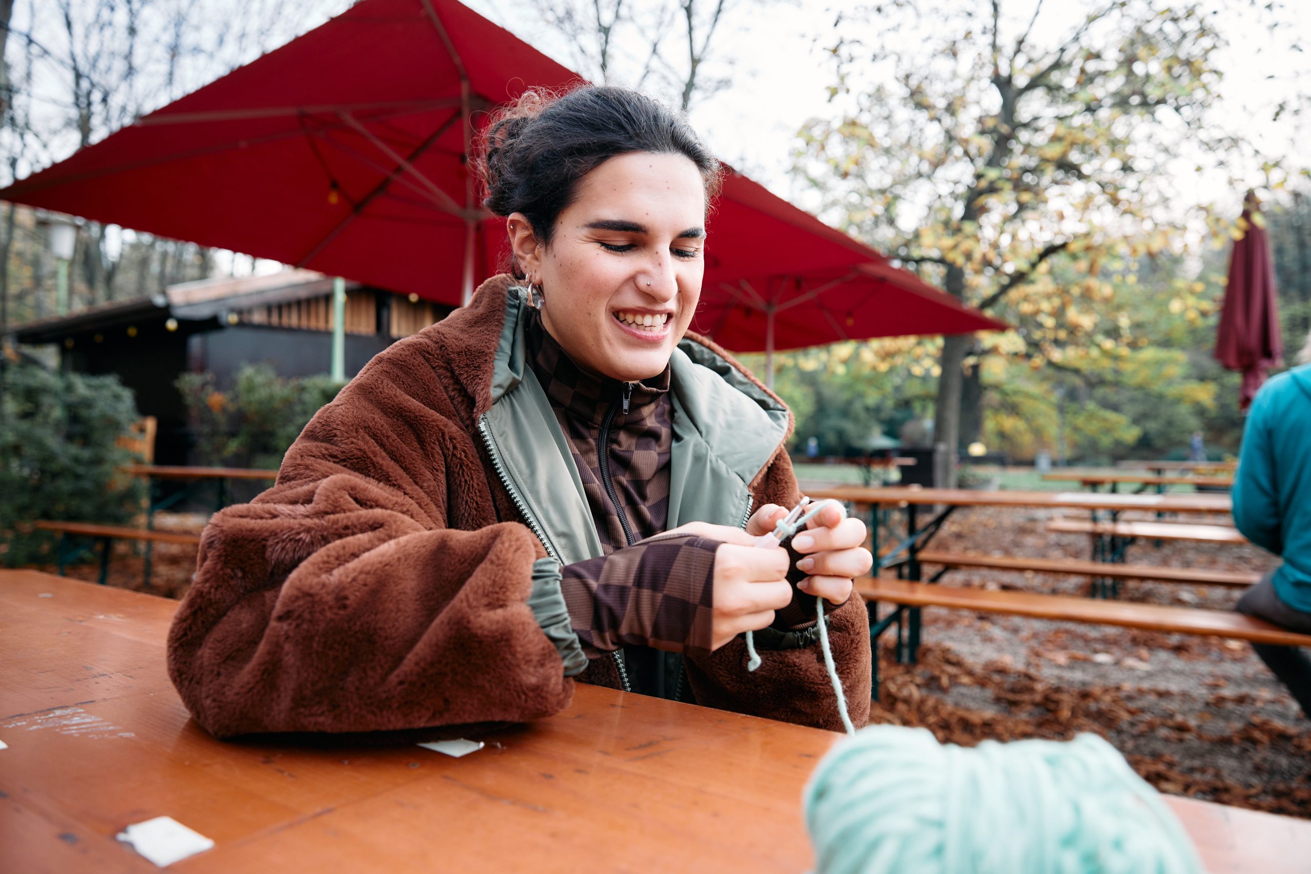 frau ist am häkeln in einem biergarten