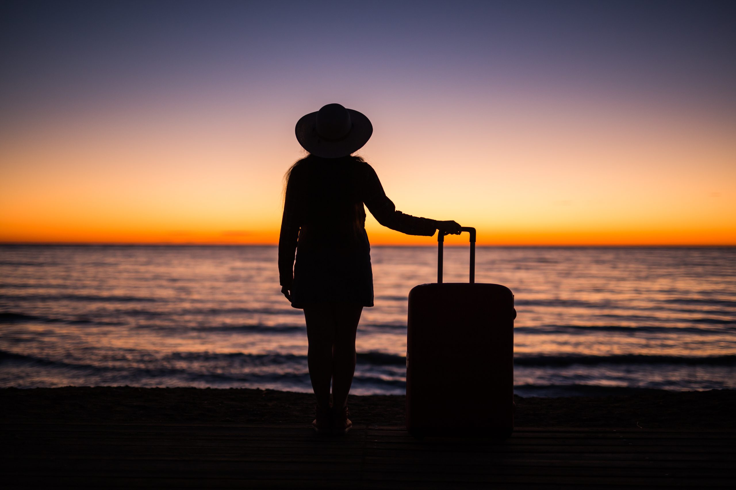 Frau mit Koffer am Strand