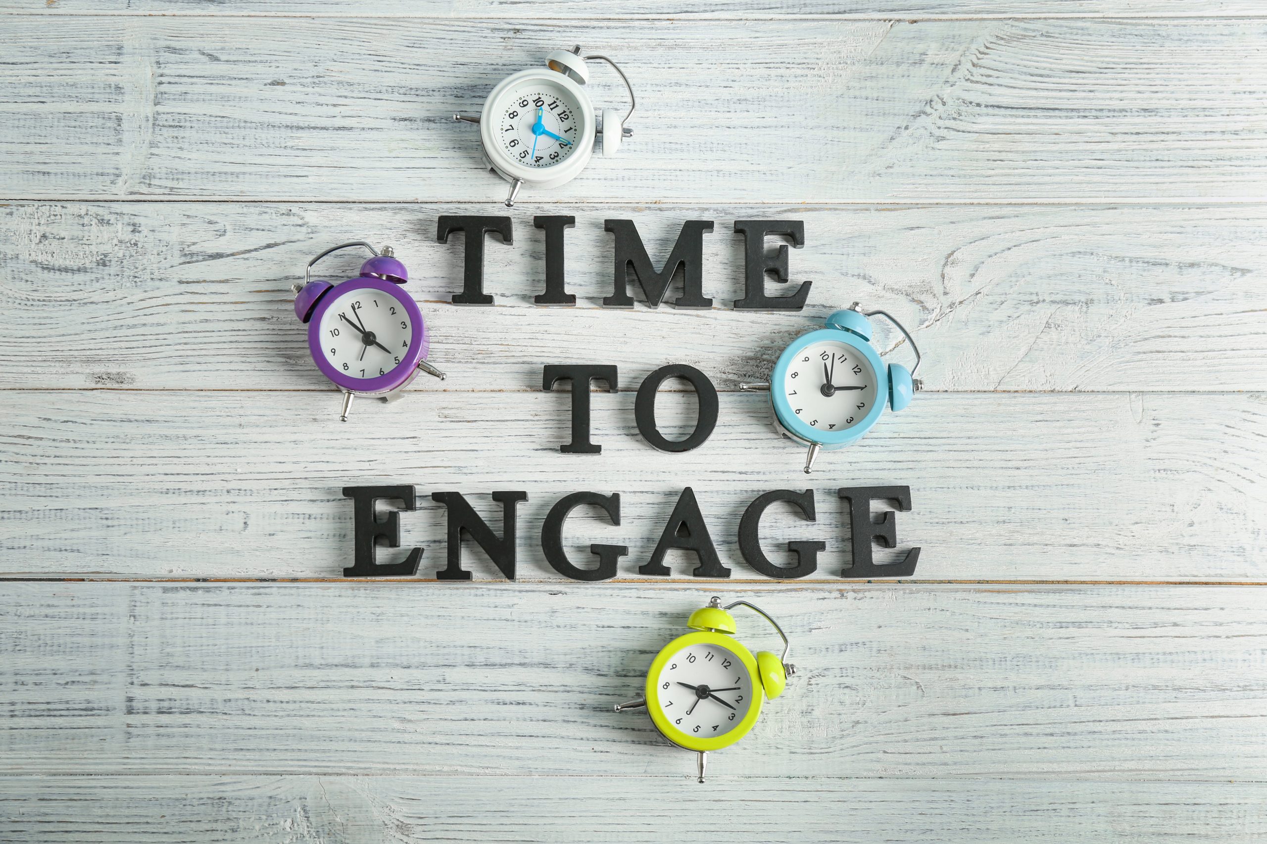 Uhren und Satz TIME TO ENGAGE (Zeit für Engagement) auf hölzernem Hintergrund