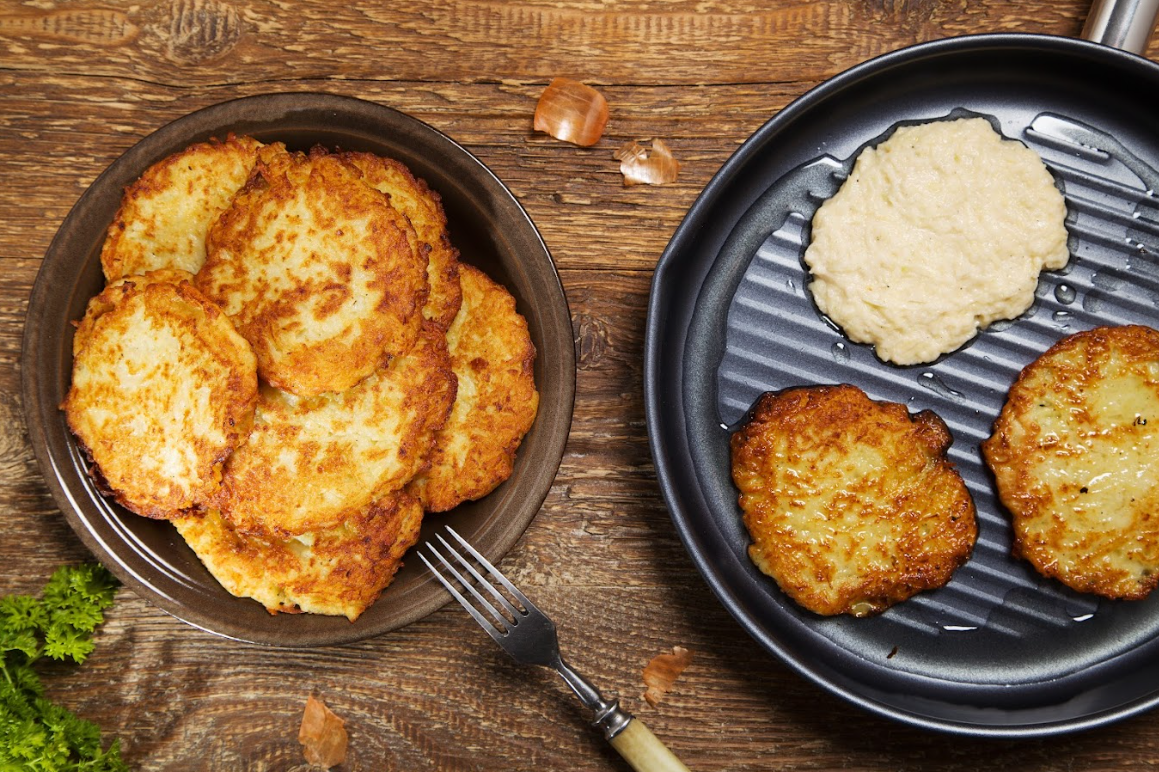 Reibekuchen in der Pfanne und auf einem Teller