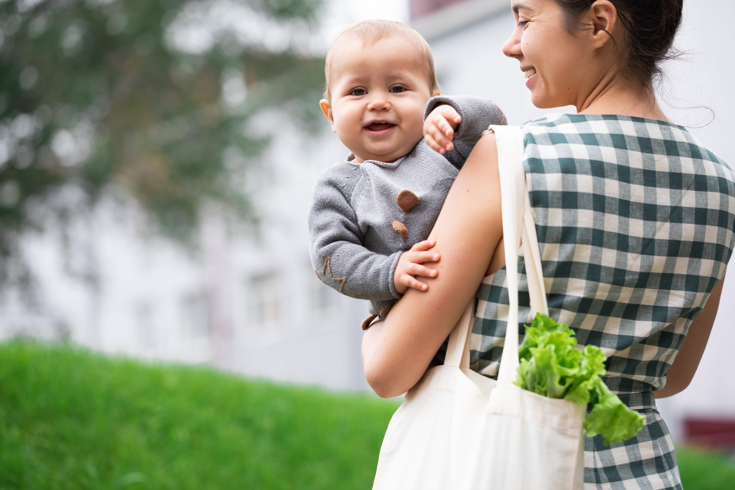 Junge Frau mit Jutebeutel und Baby auf dem Arm