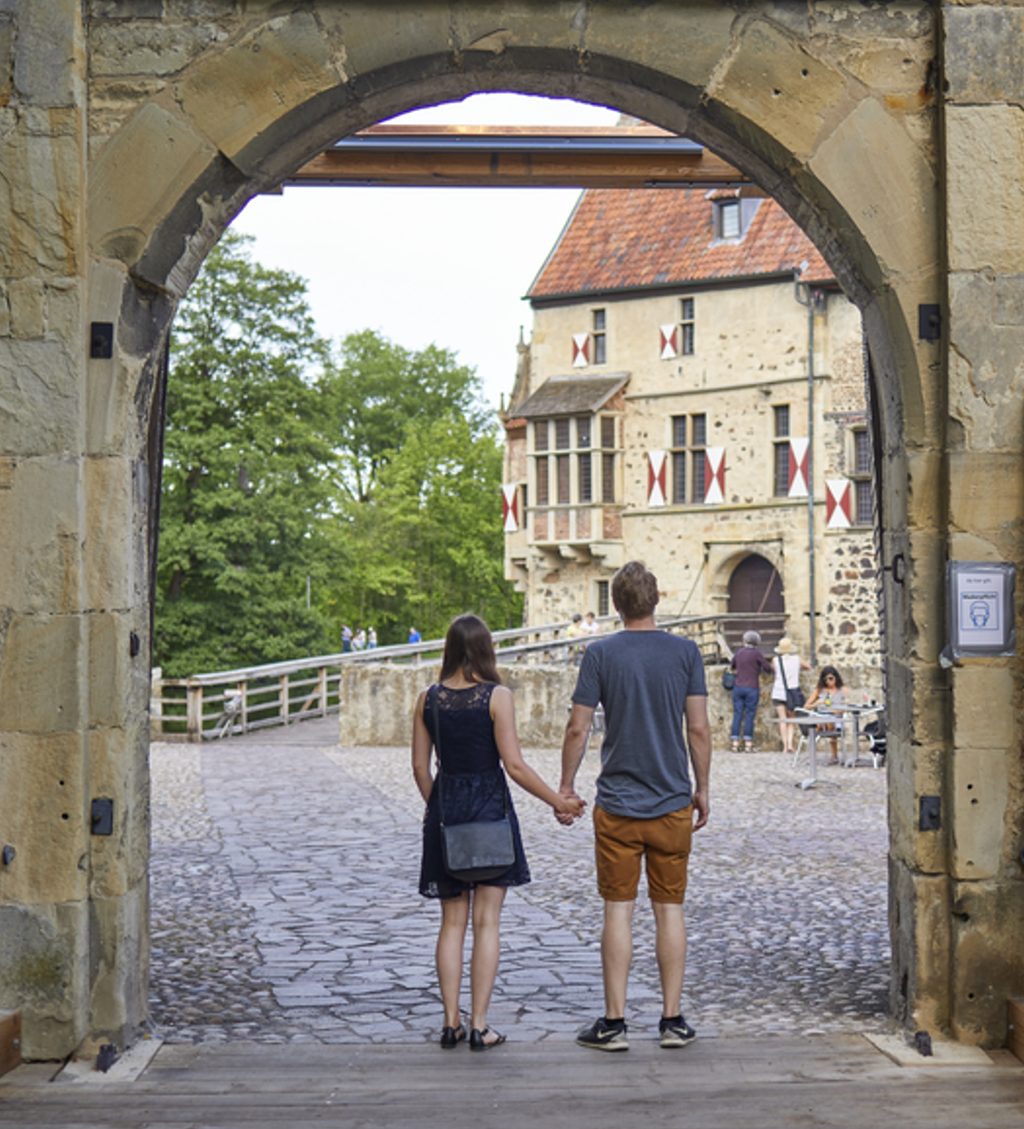 Besucher blicken über den Burghof auf die Hauptburg der Burg Vischering. Die imposante Burg liegt am Südkurs der 100-Schlösser-Route