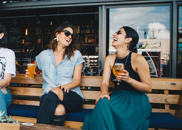 Zwei Frauen auf einer Bank mit Bierglas in der Hand