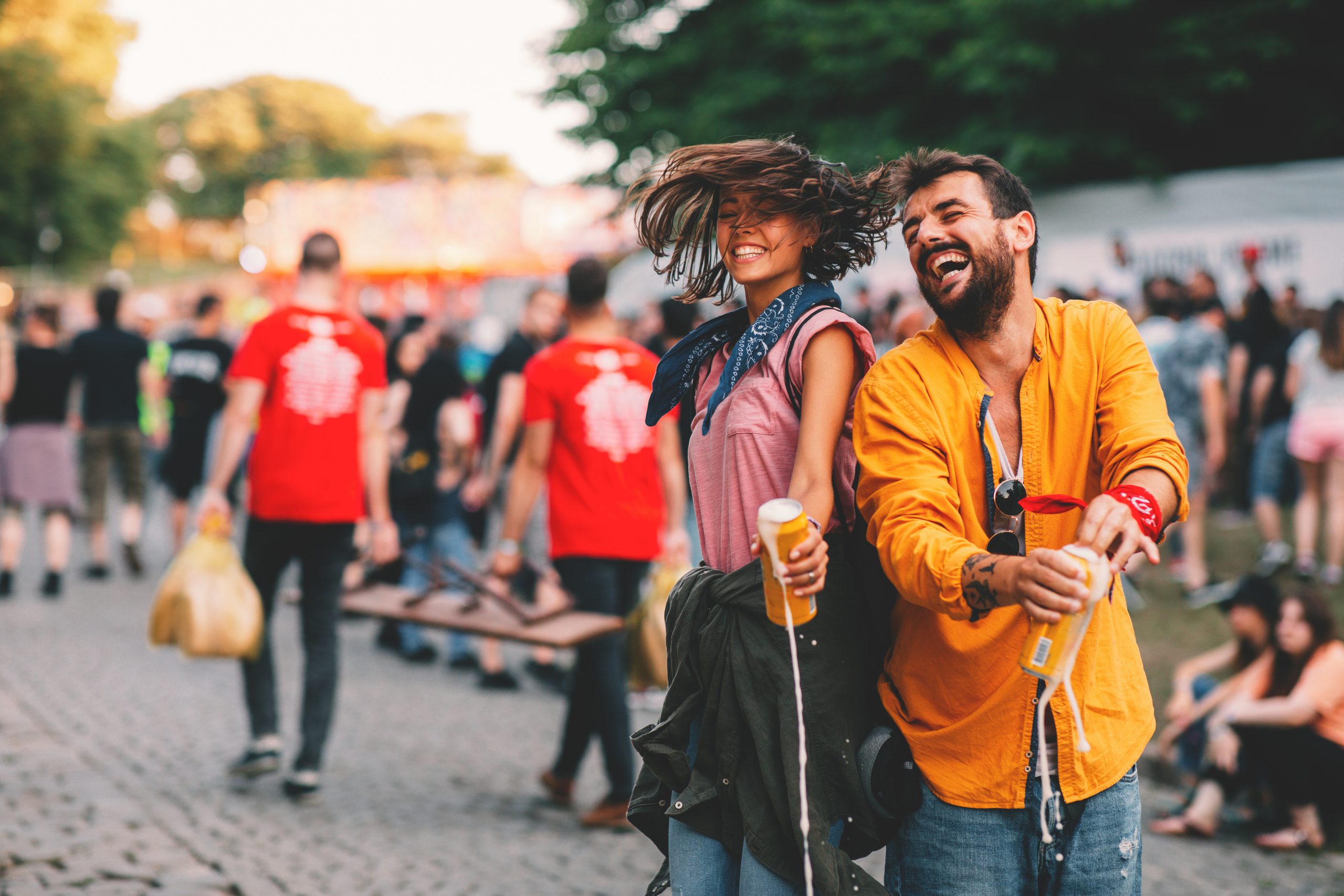 Junges Paar tanzt mit Bier in der Hand auf einem Straßenfest.