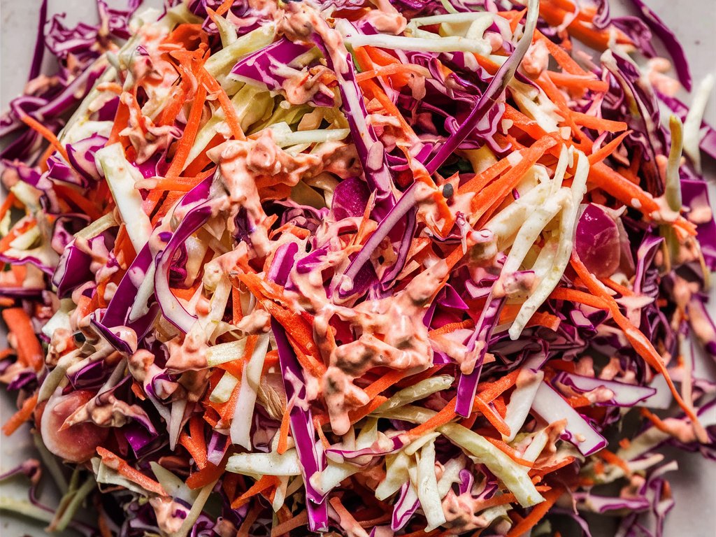 Eine Nahaufnahme eines Coleslaw-Salats aus geschnittenem Kohl, Möhren und Zwiebeln.