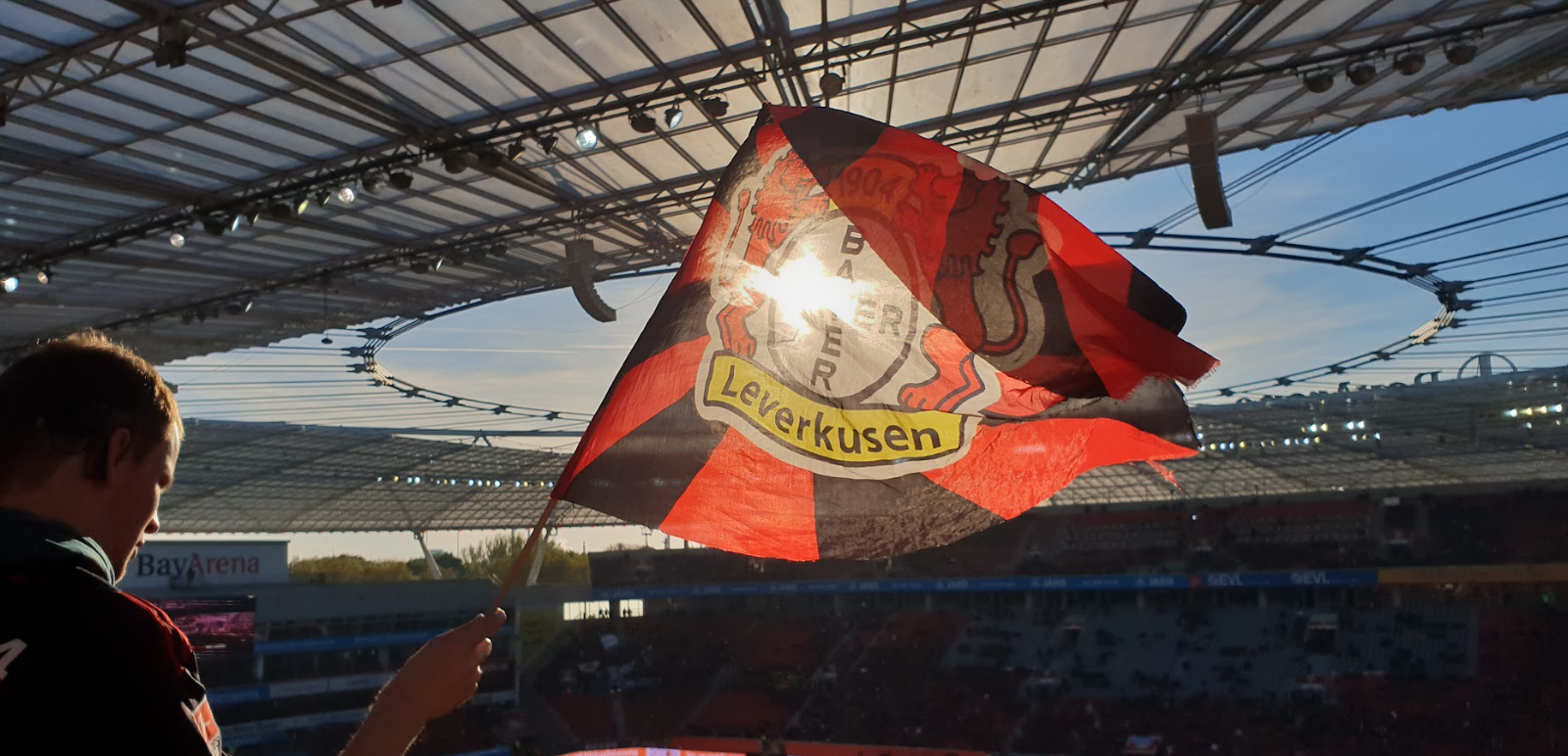 ein Fan schwenkt eine Fahne von Bayer Leverkusen