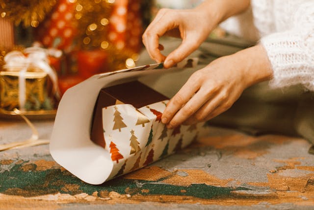 eine Frau packt ein Geschenk in Geschenkpapier